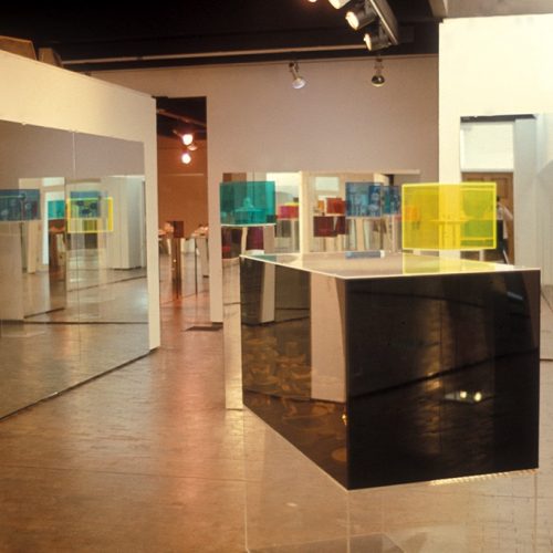 multicoloured plexiglas cubes displayed on mirrored and transparent plinths